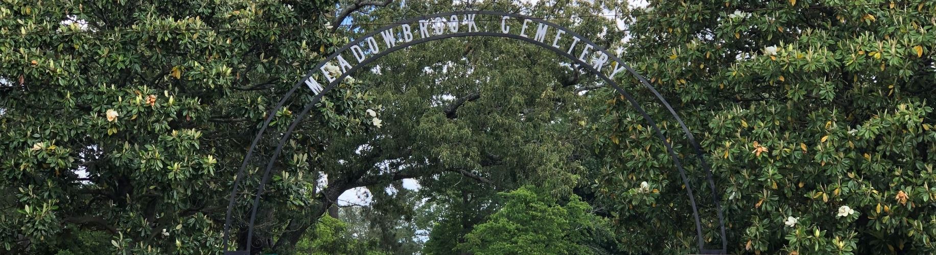 View of Meadowbrook Cemetery in Lumberton, NC with manicured grounds and headstones under a clear sky.